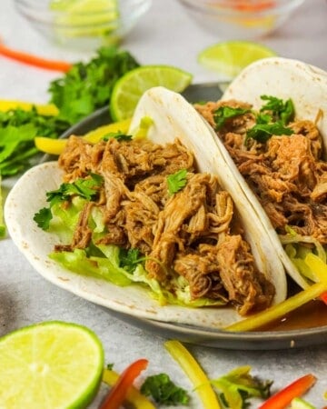 Slow cooker Pork Barbacoa tacos with cilantro and peppers.