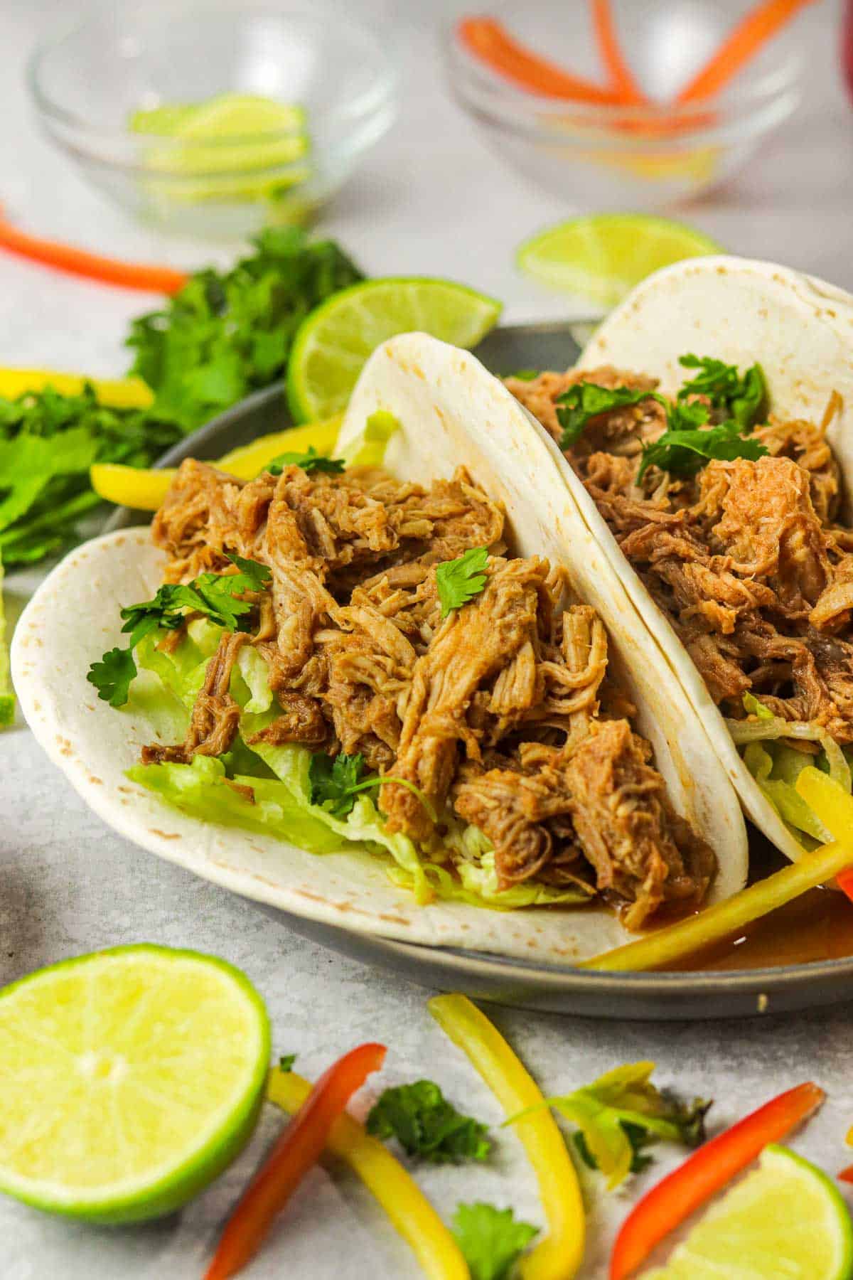 Slow cooker Pork Barbacoa tacos with cilantro and peppers.