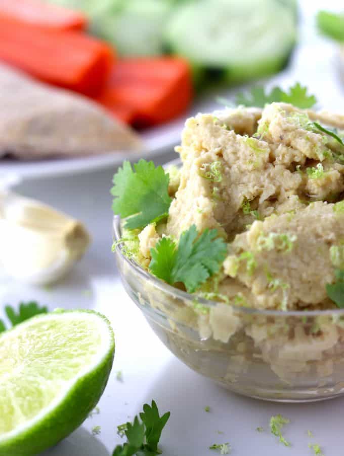 Simple roasted garlic and lime hummus in a dish with veggies and pita