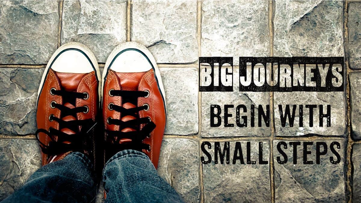 person wearing converse on a cobblestone road next to text that says big journeys begin with small steps.
