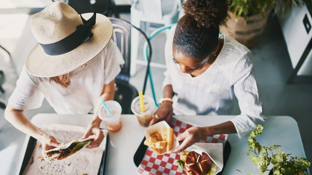 two women talking over lunch enjoying a burger and fries and a wrap.