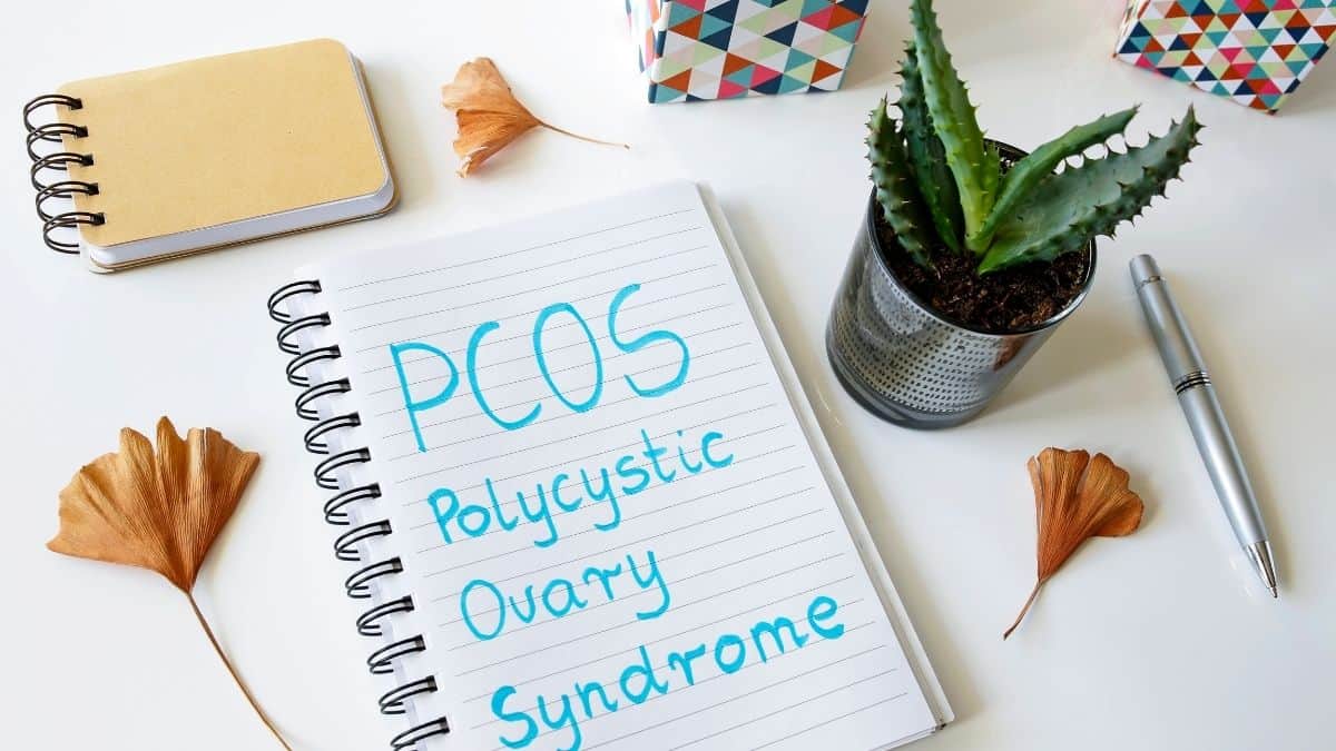 PCOS polysistic ovary syndrome written in a journal with blue marker.