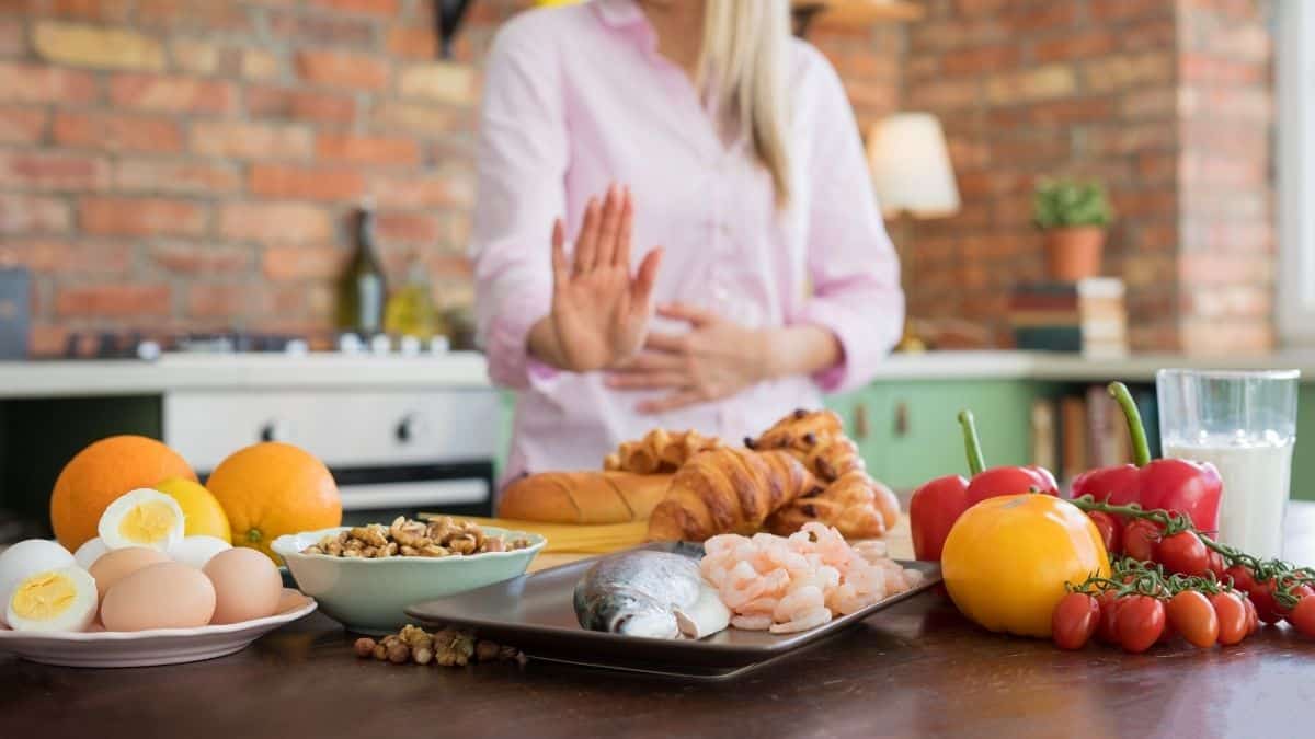 variety of food on the table with woman pushing it away not eating it.