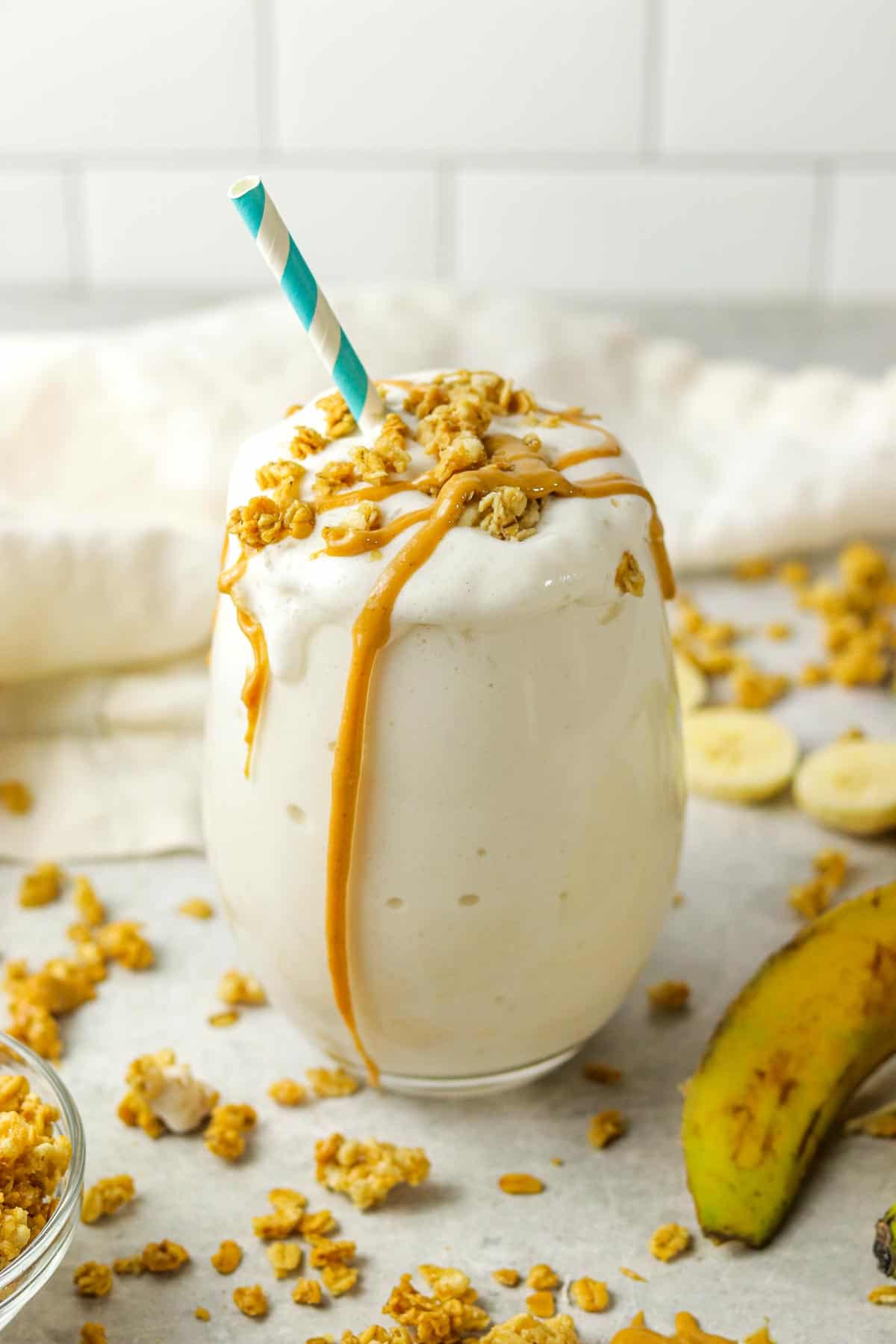 A banana protein shake with granola and peanut butter on it