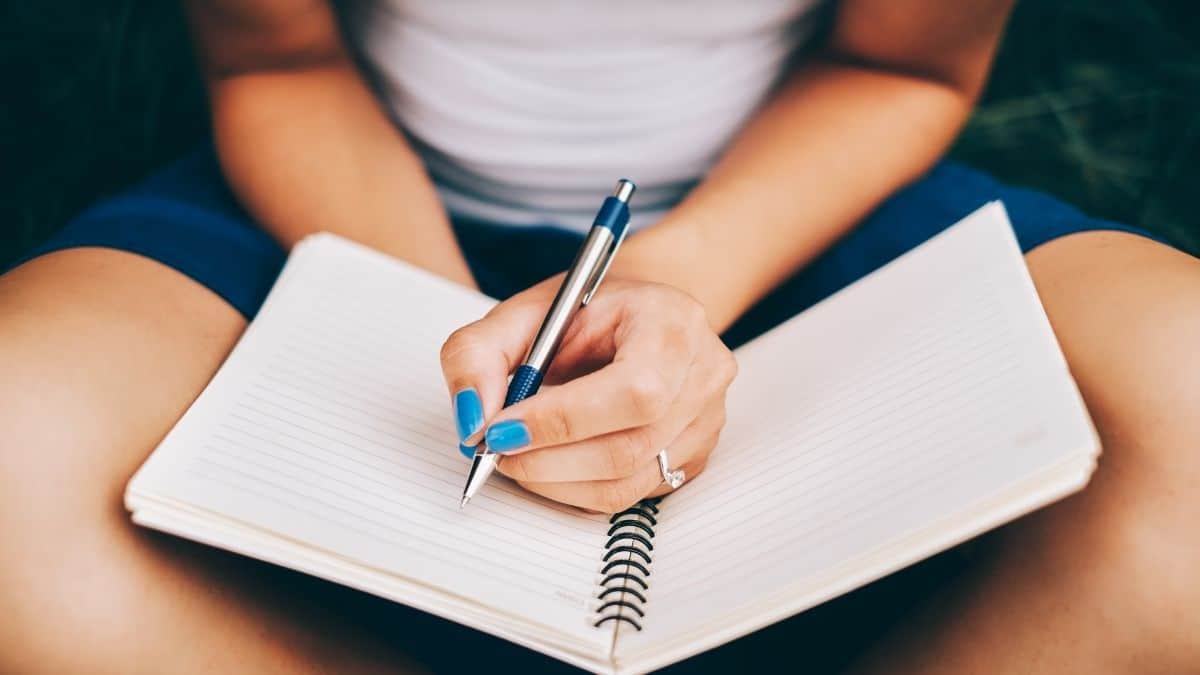 A woman sitting criss-cross writing in her journal.