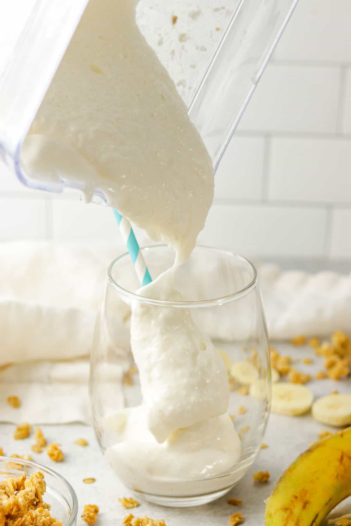 pouring a banana protein shake into a glass.