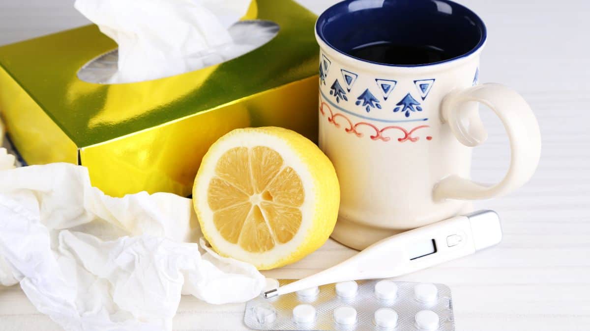 a sick day collection of tissues, tea, thermometer and medicine on a countertop.