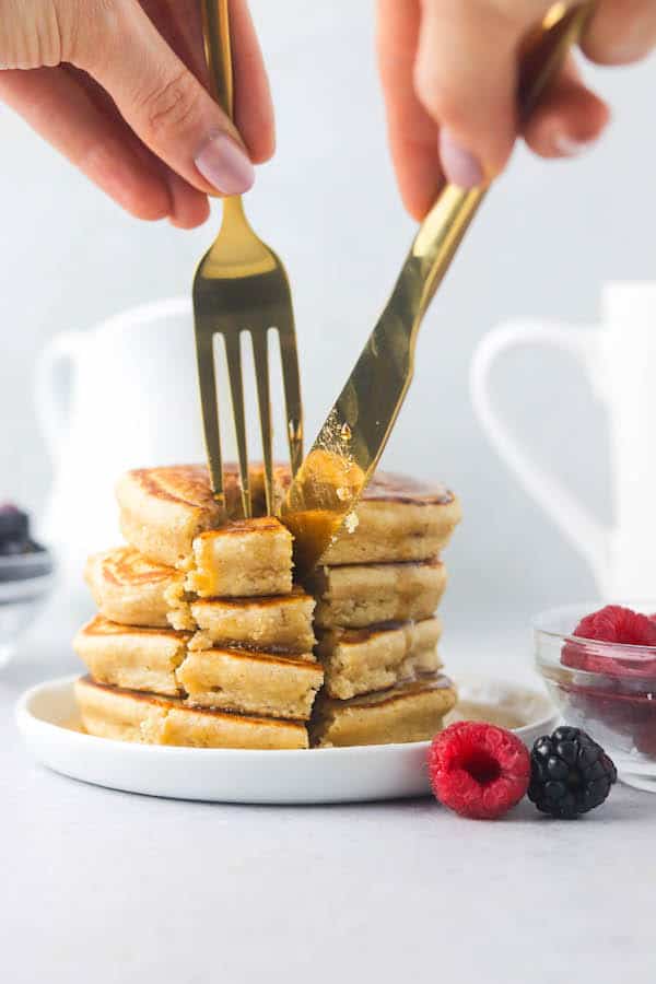 A knife and fork cutting into oat flour pancakes