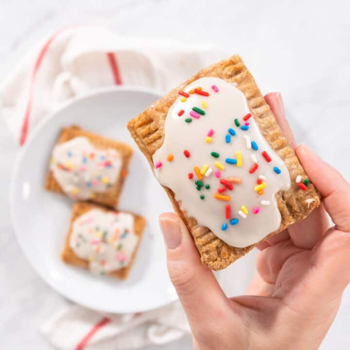 Holding a vegan pop tart with frosting and sprinkles