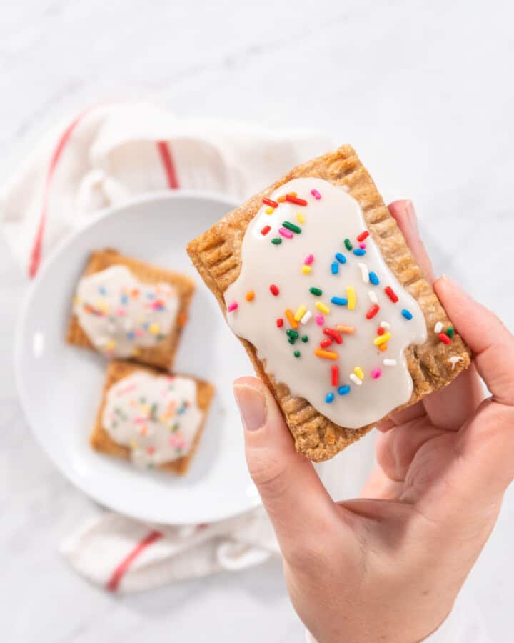 Holding a vegan pop tart with frosting and sprinkles