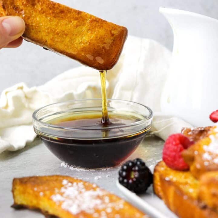 Dipping an air fryer french toast stick int maple syrup.