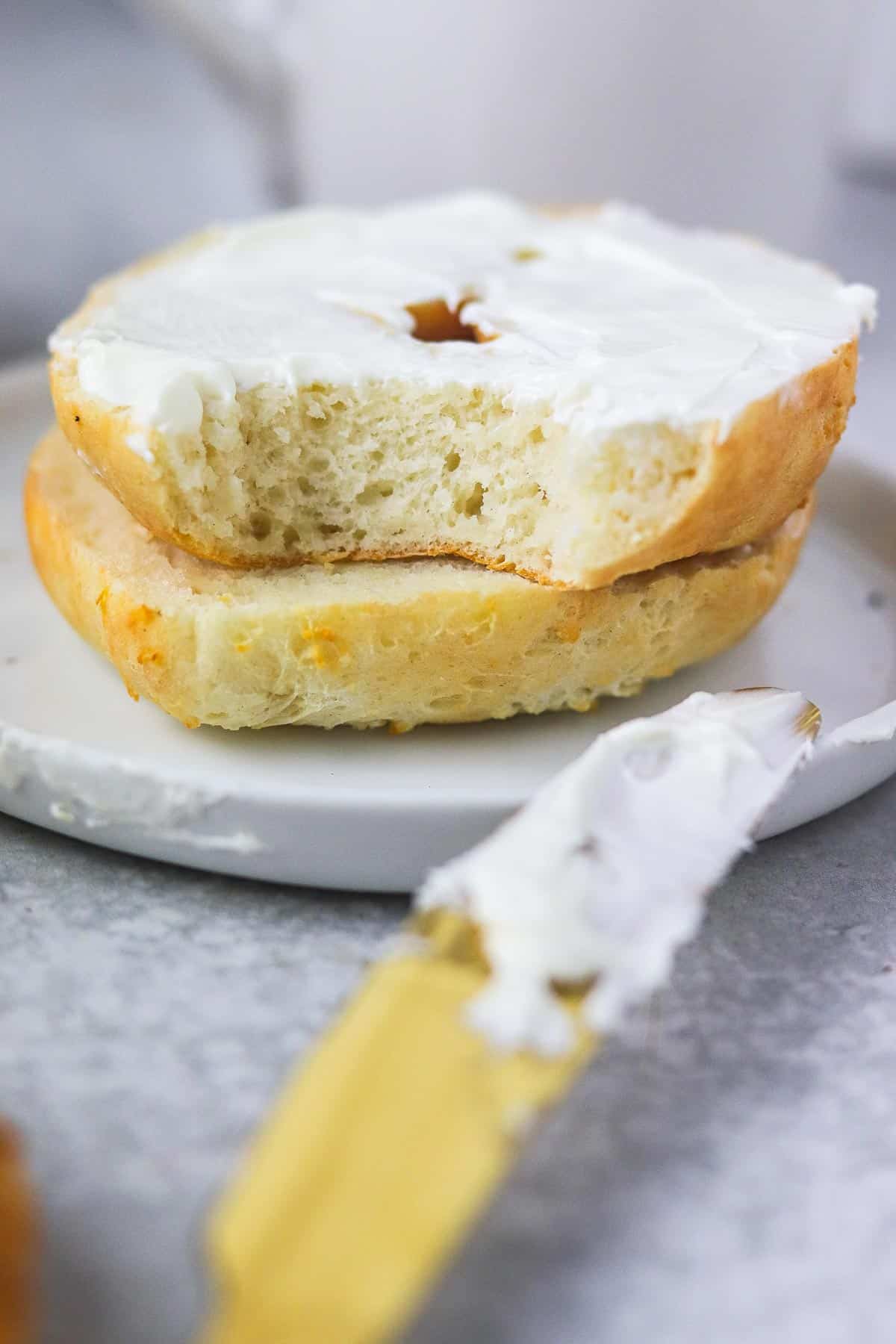 3 ingredient bagel with cream cheese with a bite out of it.