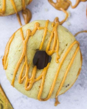 Baked banana donut with peanut butter drizzled over it.