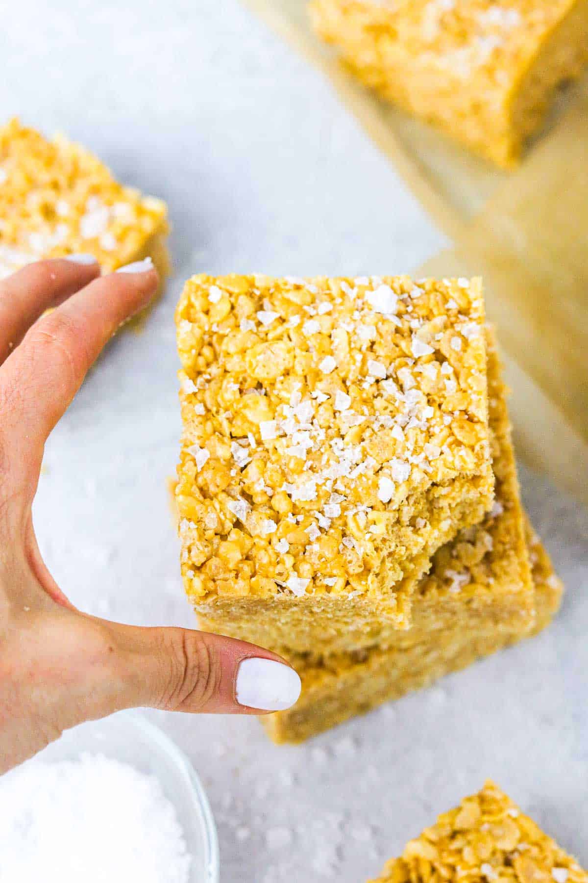 grabbing a Peanut butter rice krispie bar off of a stack