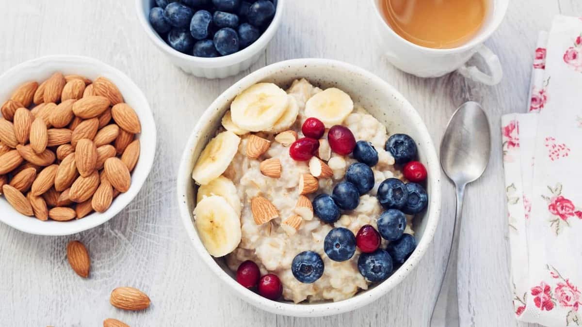 A bowl of oatmeal on a table with berries and nuts.