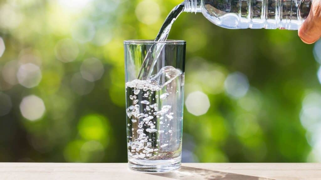 A bottle of water being poured into a glass.