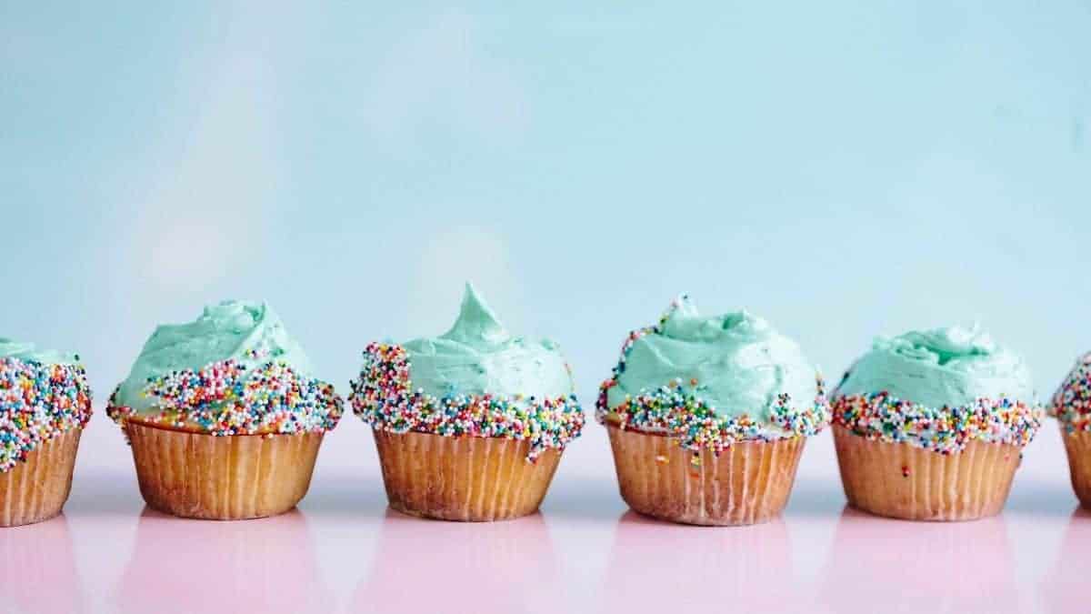 blue cupcakes in a line with sprinkles.