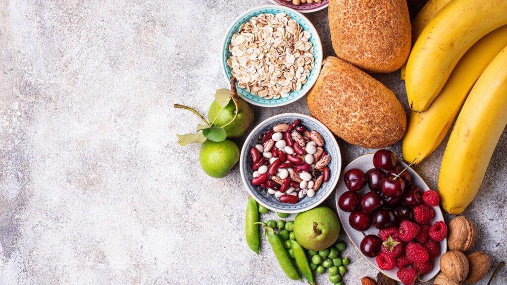 a variety of fruits, beans, and bread on a plaster background on the right side.