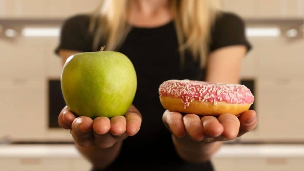 holding an apple and donut for flexible dieting