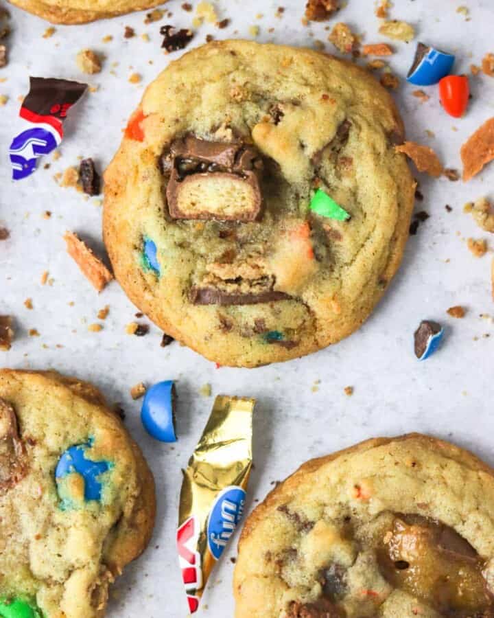 A close up of candy bar cookies with candy pieces around them.