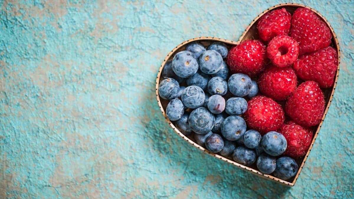 A heart shaped bowl with berried in it.