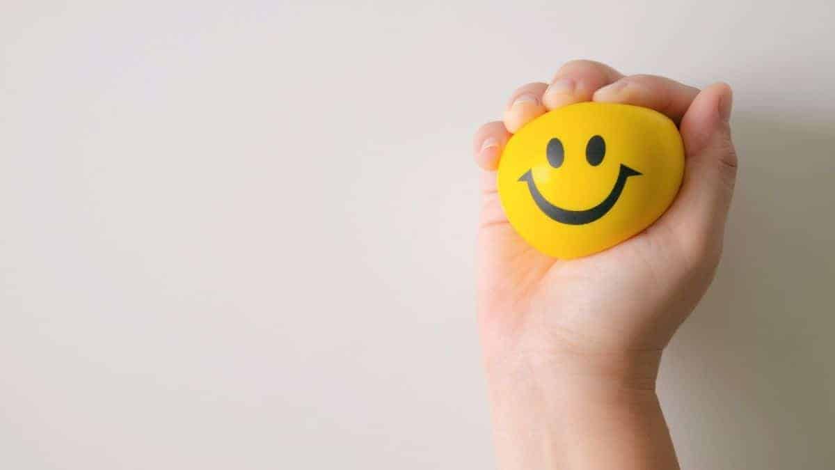 A hand holding a smiley face stress ball.
