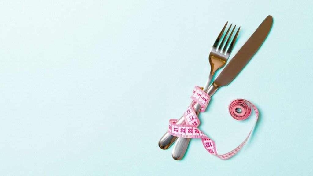 fork and knife with pink tape measure weight loss.