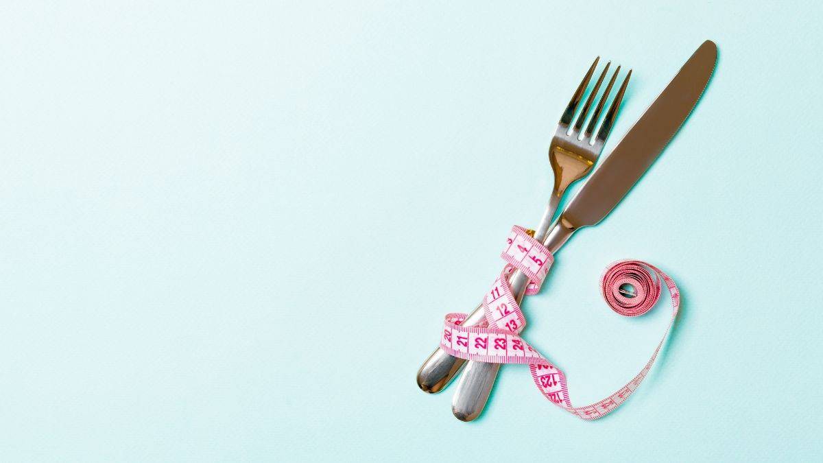 fork and knife with pink tape measure weight loss.