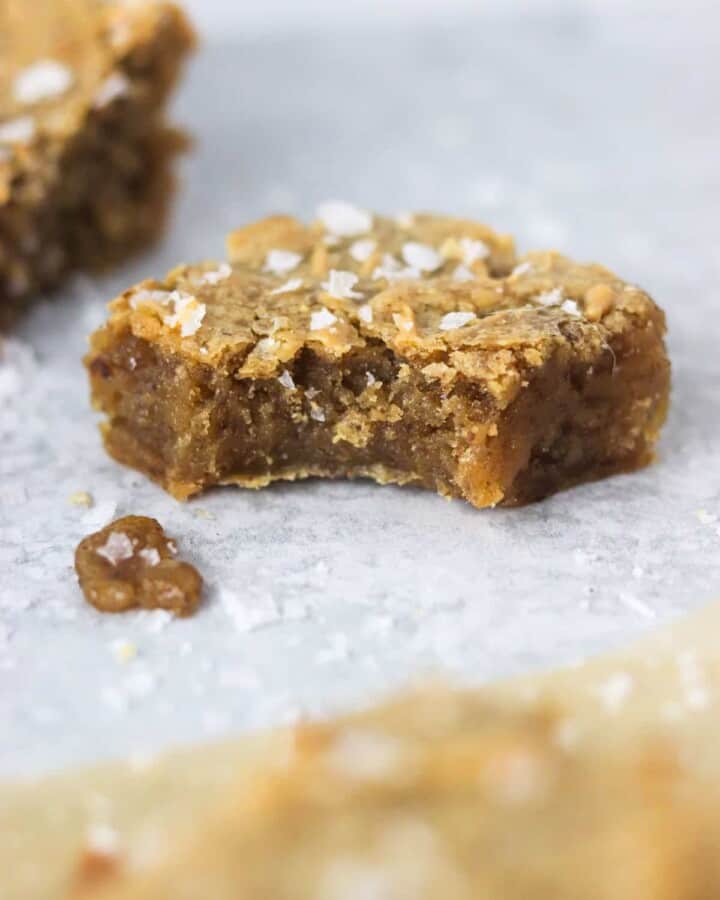A close up of a gooey peanut butter vegan blondie with a bite out.