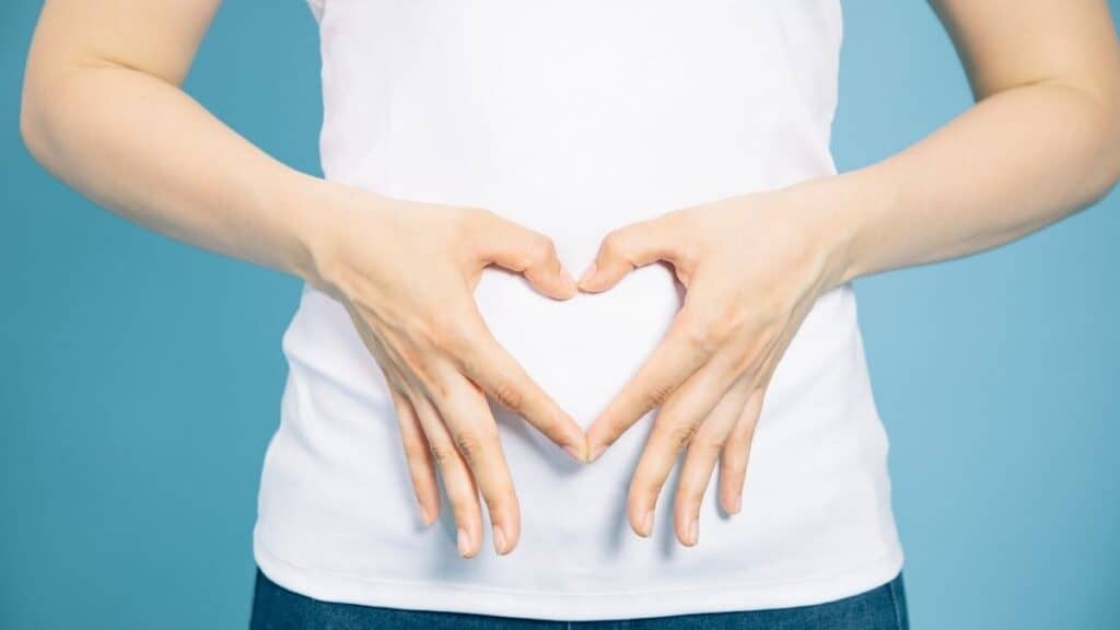 A woman holding her hands in a heart shape over her stomach symbolizing gut health.
