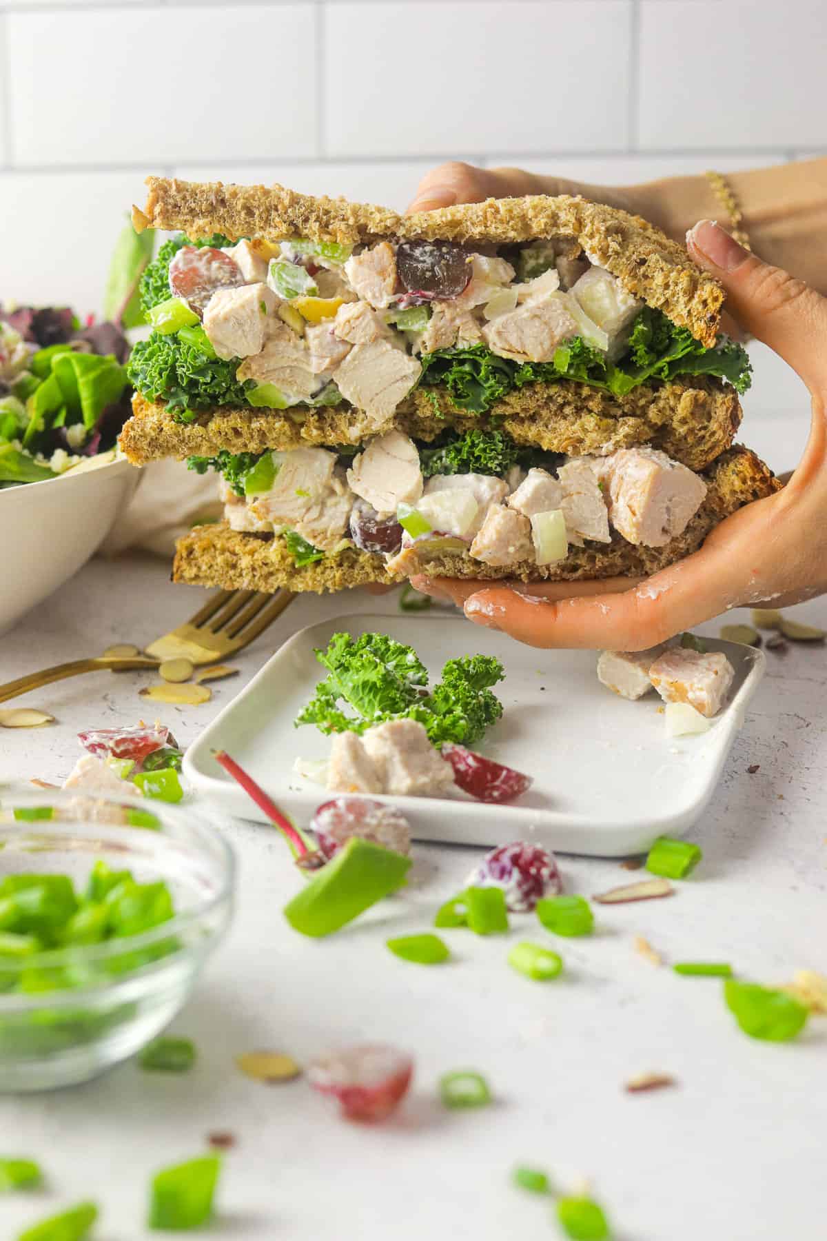 holding turkey salad with grapes sandwich.