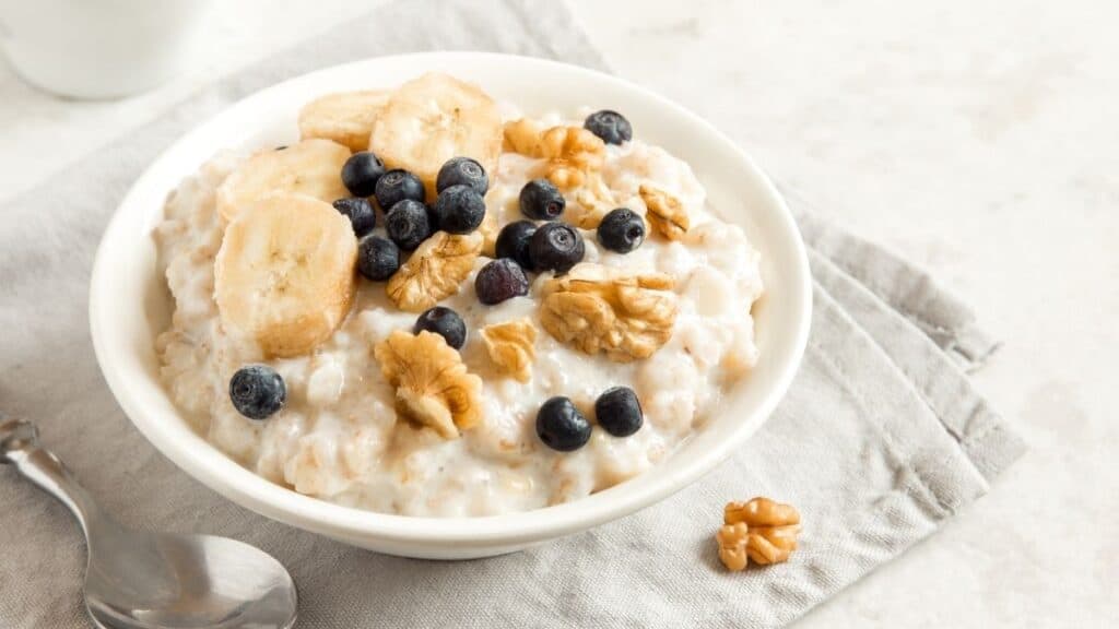 A bowl of oatmeal topped with blueberries, nuts and banana.
