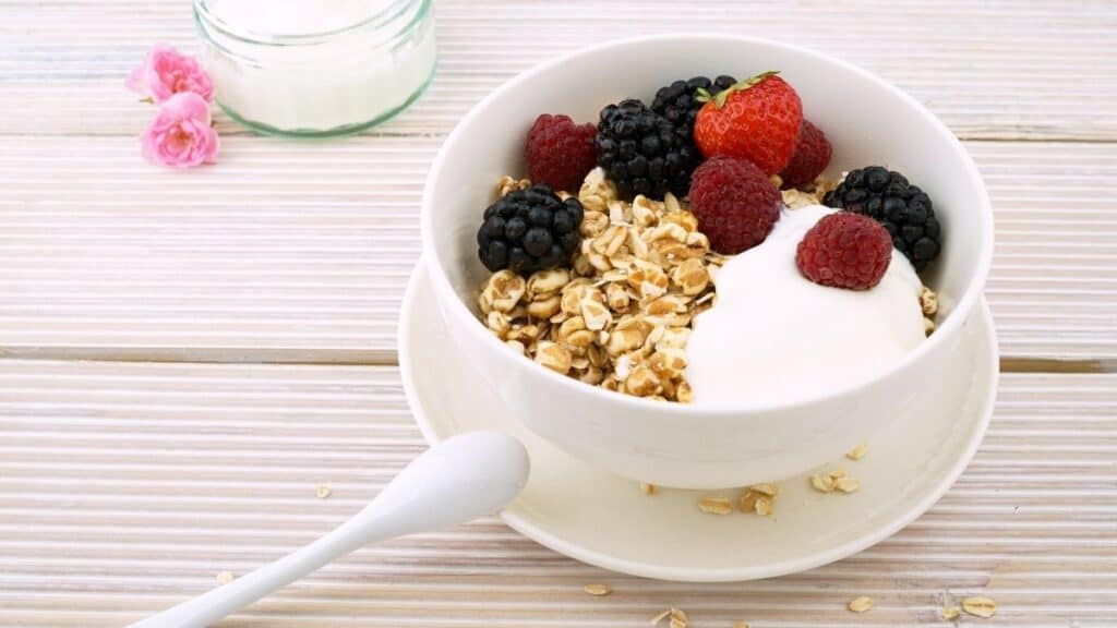 A white bowl of rolled oats with berries on top.