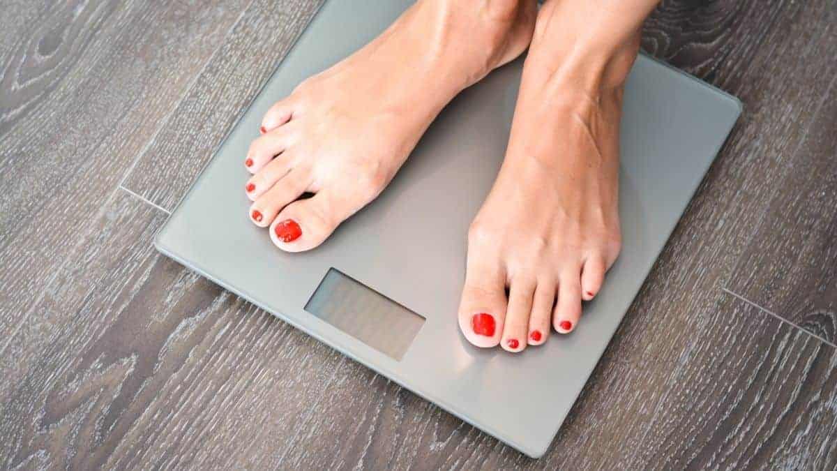 Feet with red painted toes standing on a weight scale.
