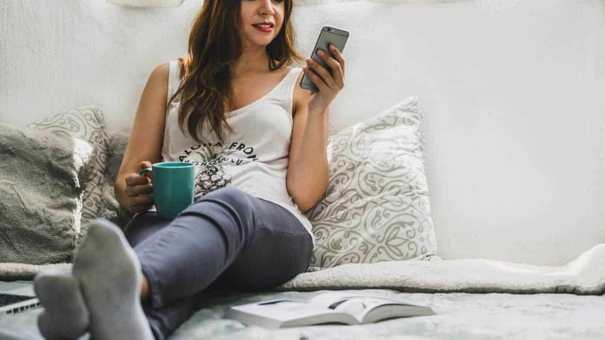 A woman sitting on a bed talking on the phone.