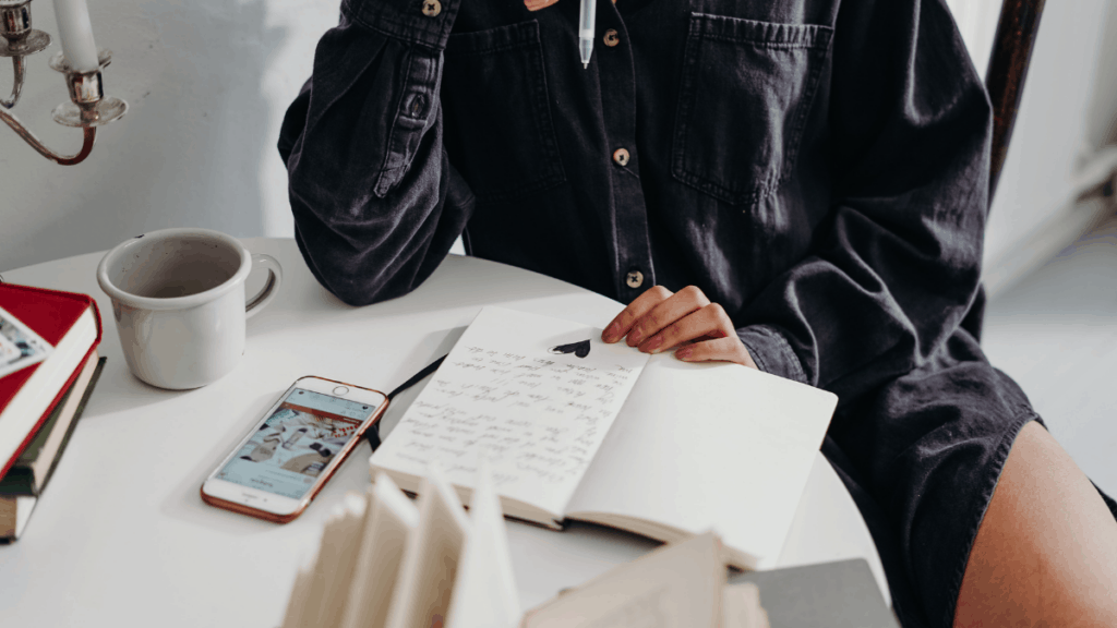 A woman writing in a journal at the kitchen table.