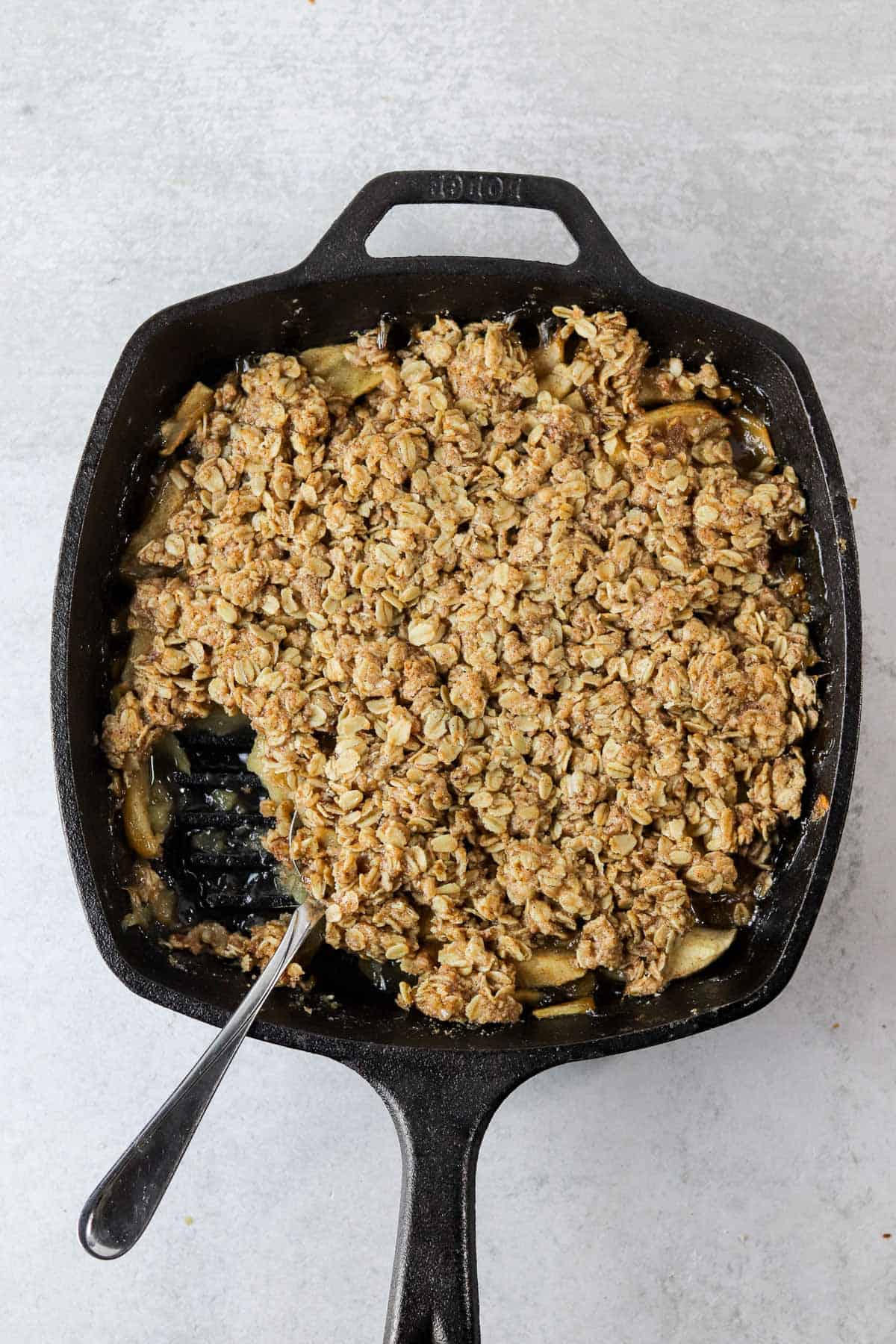 Baked skillet apple crisp with a scoop removed.