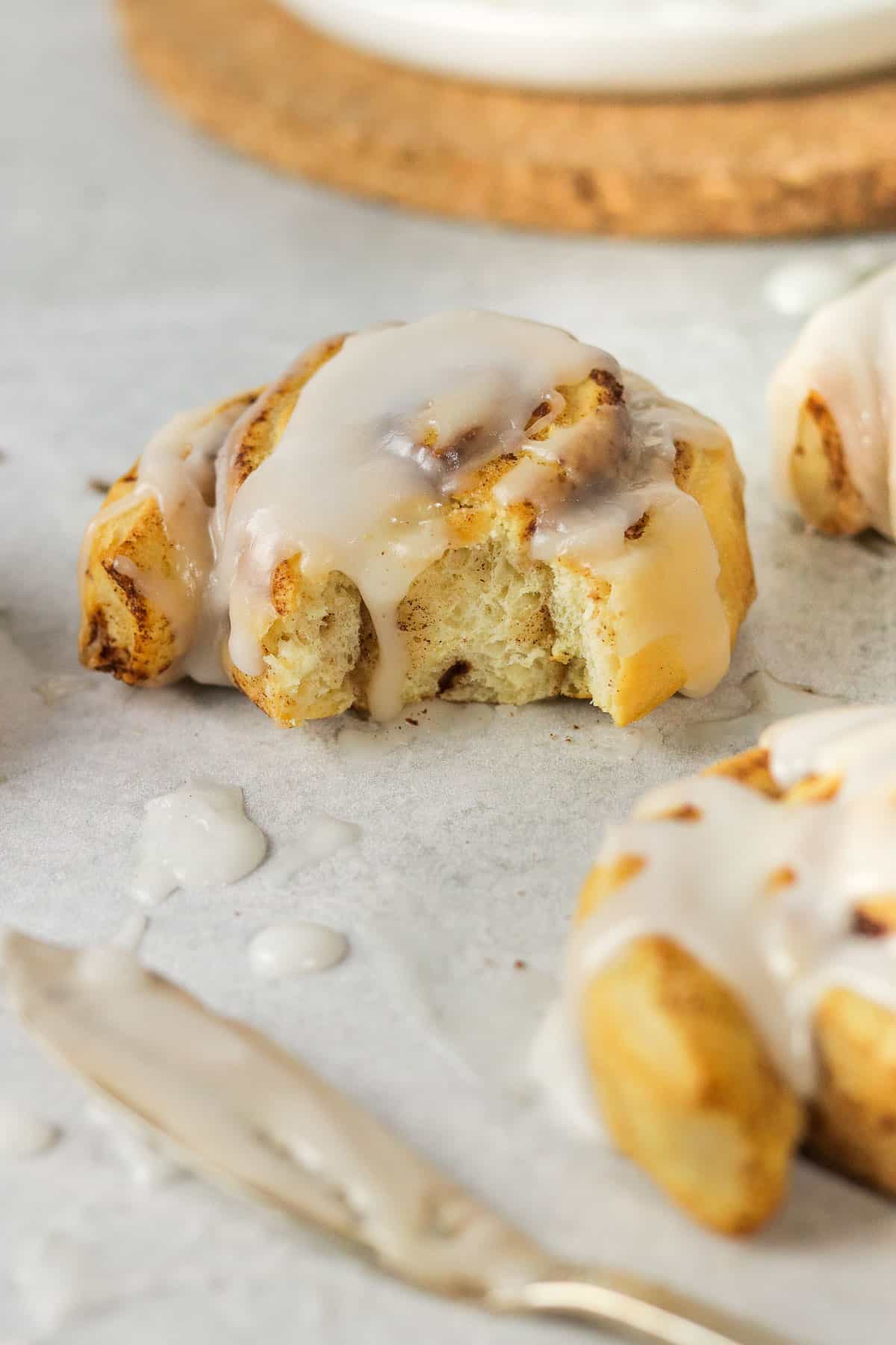 gooey frosted air fryer cinnamon roll with a bite out of it.