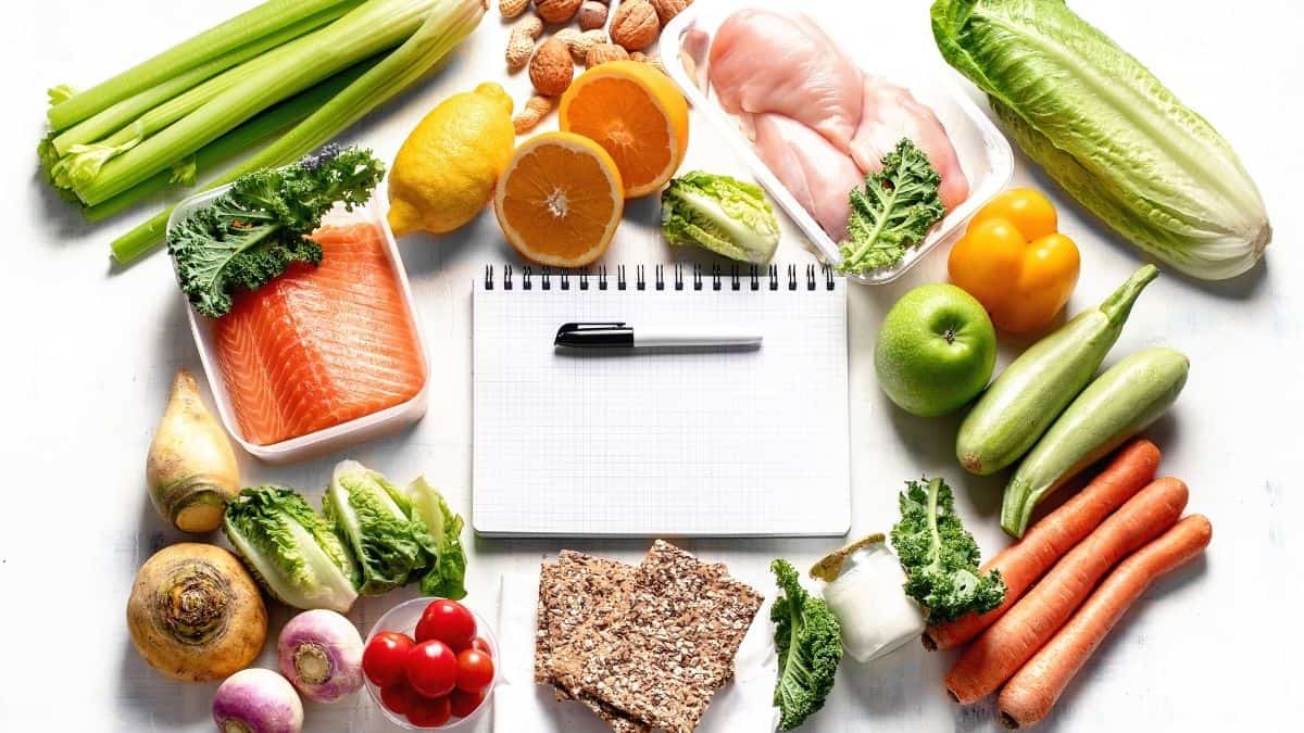 Meal planning notebook surrounded by healthy foods.