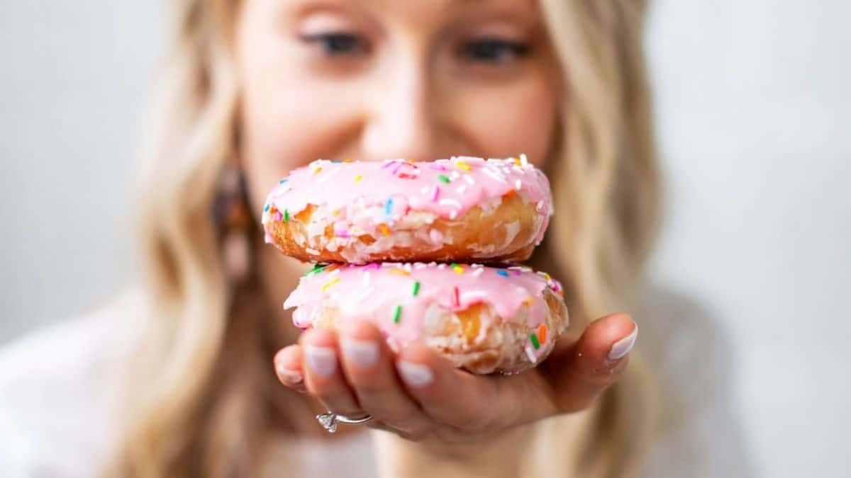 Colleen Christensen, Registered Dietitian, holding 2 pink donuts with sprinkles in her hand.