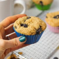 holding a gluten free blueberry muffin.