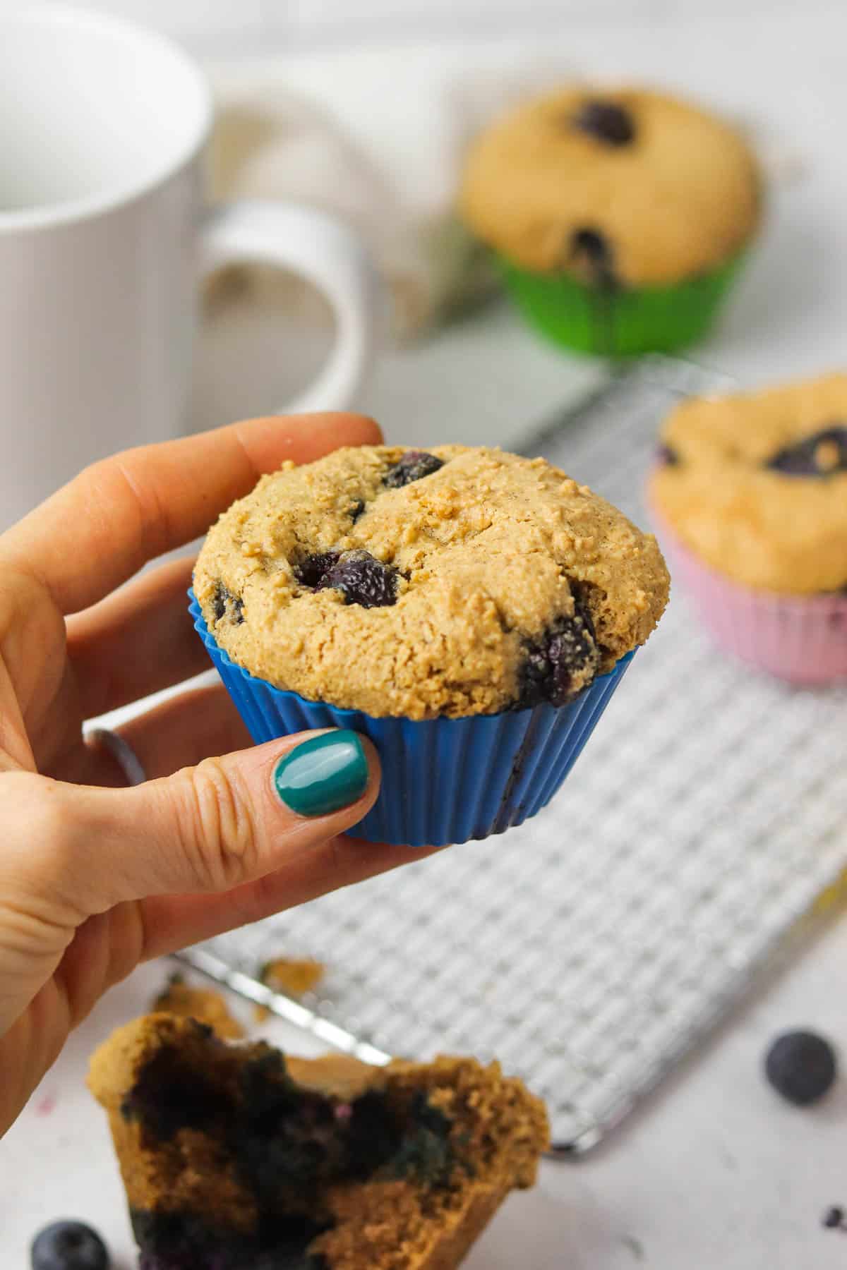 holding a gluten free blueberry muffin.