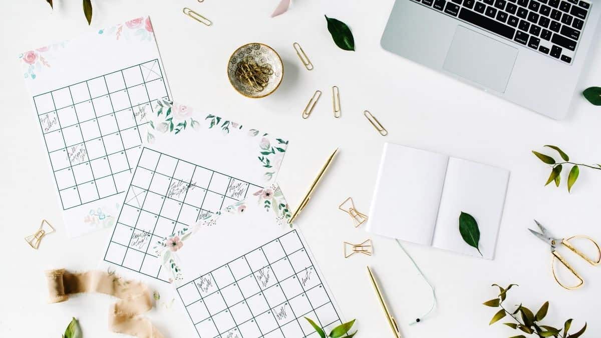 Blank planner calendar pages with paper clips and a laptop.