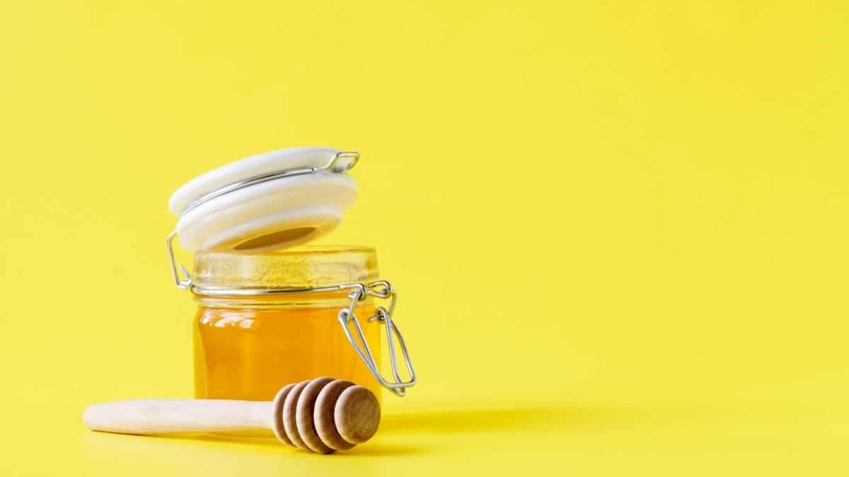 Jar of honey on a yellow backdrop.