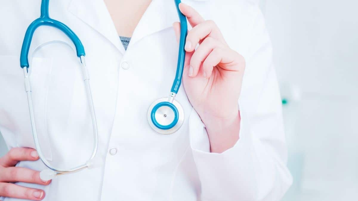 A healthcare professional in a lab coat wearing a blue stethoscope.