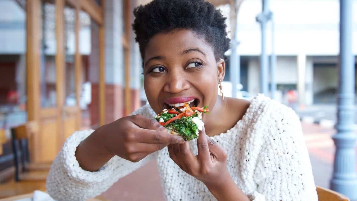 a woman eating pizza in a white sweater.