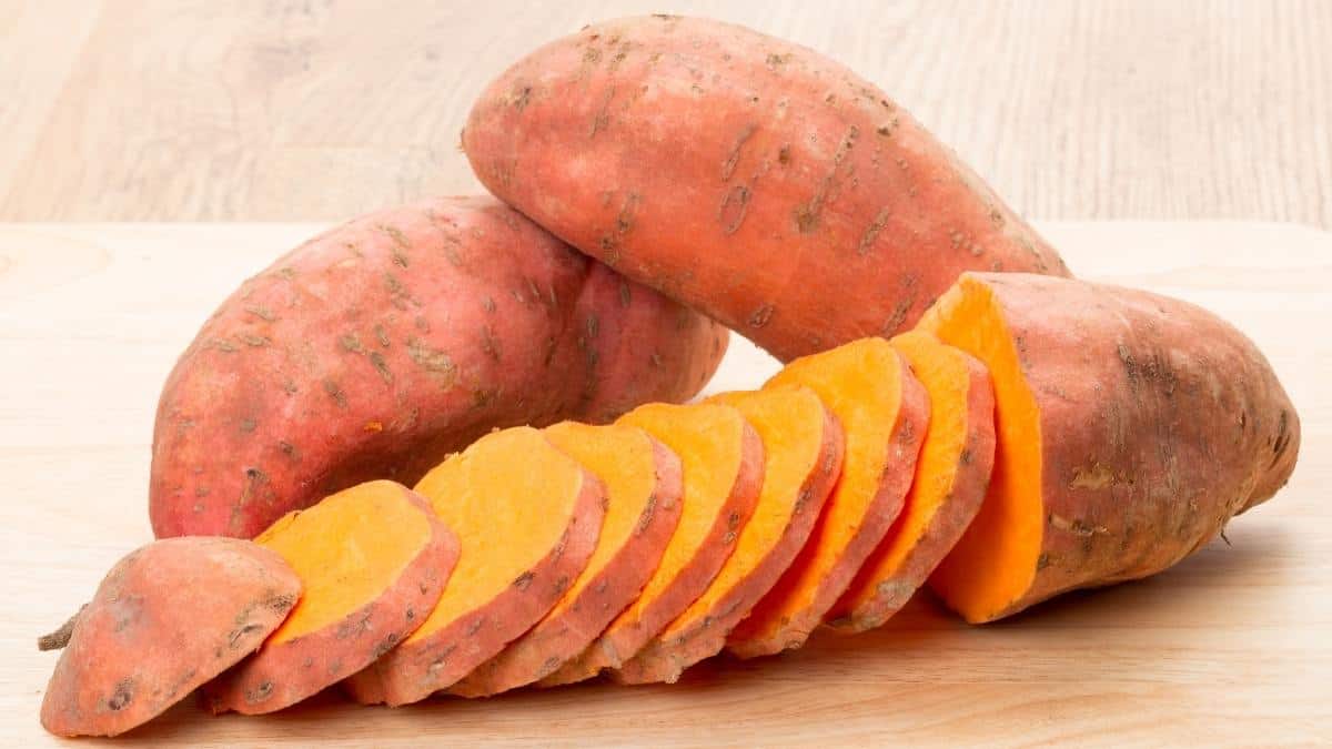 Sweet potatoes whole and sliced on a cutting board, an example of anti-inflammatory foods.