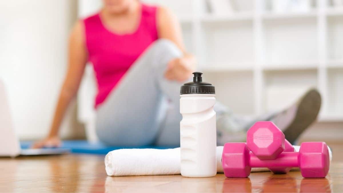 Woman stretching after a workout with a water bottle and weights.