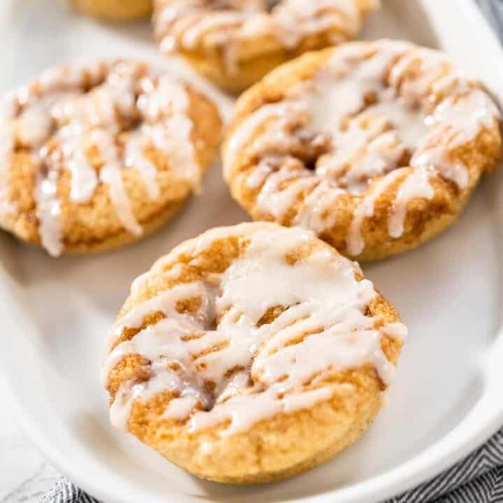 A plate of cinnamon roll donuts with frosting.