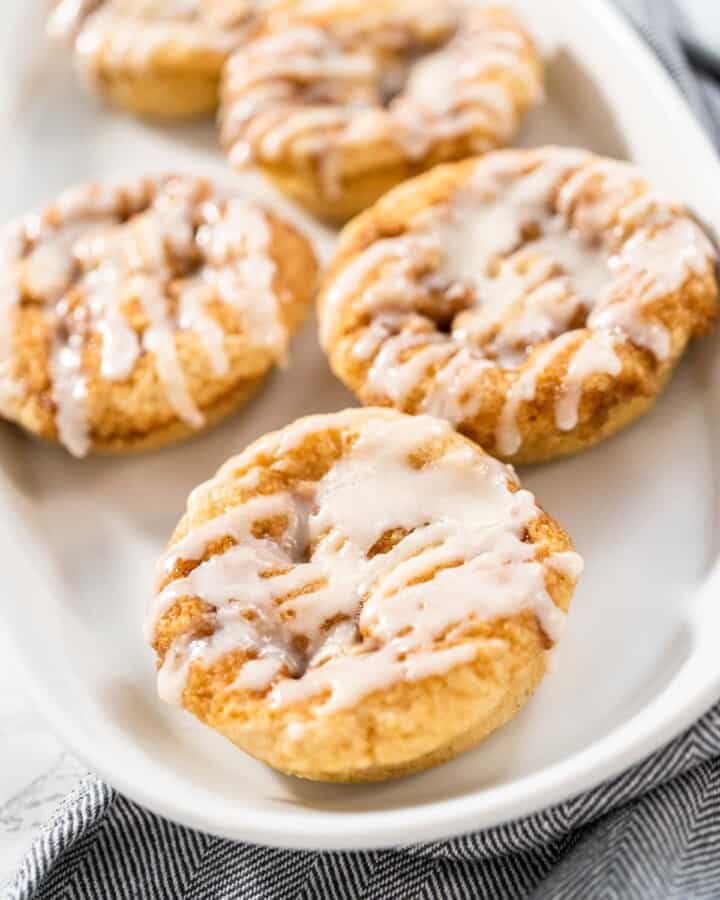 A plate of cinnamon roll donuts with frosting.